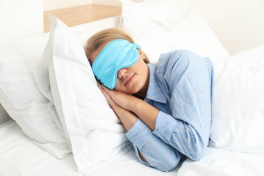Genç bir kadın uyku maskesiyle uyuyor.