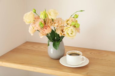 Masada çiçekler olan bir vazo ve kahve.