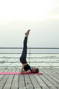 Yoga minderinde genç bir kız ahşap zeminde açık havada