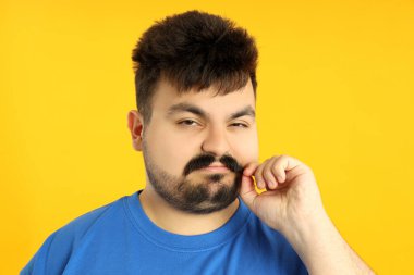 Şişman bir adam eğitimden sonra yorgun, sarı bir arka planda..