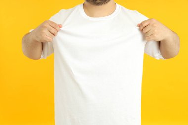 Beyaz tişörtlü, sarı arka planda bir adam..