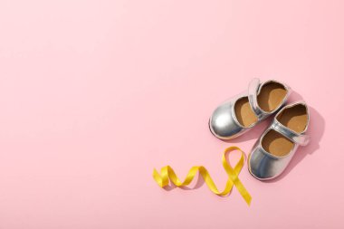 Sarı kurdeleli gümüş çocuk ayakkabıları.