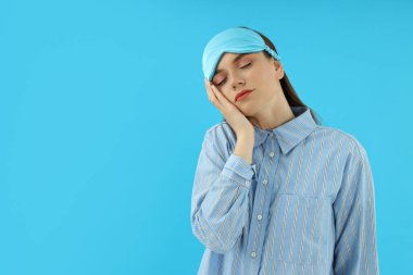 Mavi arka planda oturan çekici genç kız.