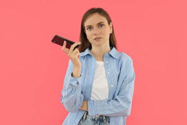 Çekici bir genç kız elinde bir akıllı telefon tutuyor.