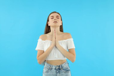 Çekici bir genç kız mavi bir arka planda duruyor.