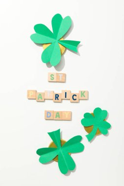 Kağıt yonca yaprakları, altın sikkeler ve beyaz arka planda harfler.