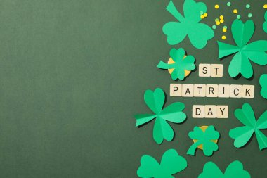 Kağıt yonca yaprakları, altın sikkeler ve yeşil arkaplanda harfler, metin için boşluk