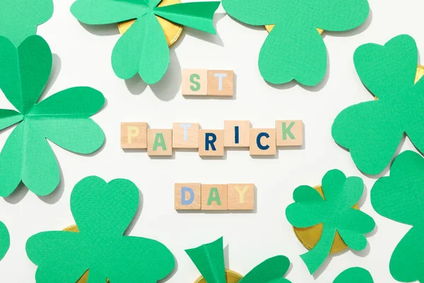 Kağıt yonca yaprakları, altın sikkeler ve beyaz arka planda harfler.