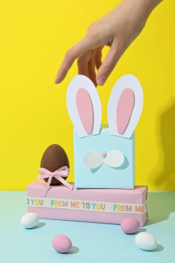 Sarı arka planda tavşan kulakları olan mavi hediye kutusu.