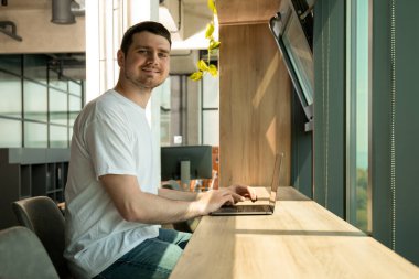 Neşeli genç bir girişimci modern bir çalışma alanında çalışır.