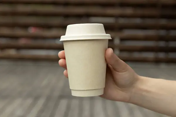 Coffee in a cardboard cup in hand.