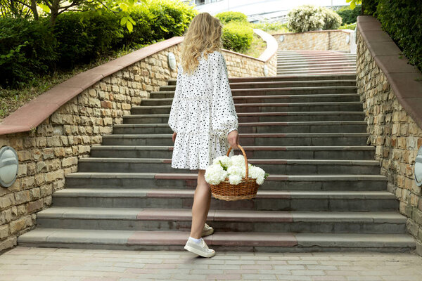 Красивая девушка с цветами на улице летом.