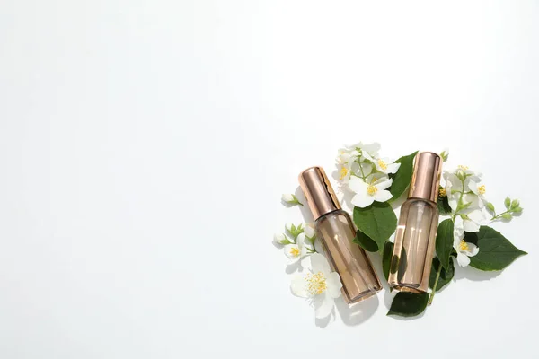 Jasmine flowers and bottle of perfume on white background, space for text