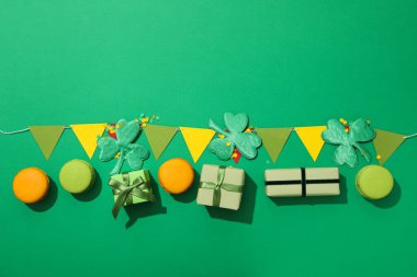 Yonca yaprakları, kağıt bayraklar, hediye kutuları ve yeşil arka planda badem kurabiyeleri.