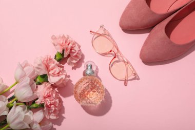 Çiçekler, kadın parfümü, pembe arka planda gözlük ve ayakkabılar, üst manzara.