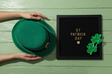 Yeşil ahşap zemin üzerinde metin, gözlük ve yeşil şapkalı siyah harf tahtası, üst görünüm