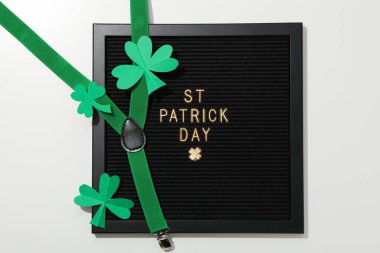 Beyaz arka planda siyah harfler, kağıt yonca yaprakları ve askılar, üst görünüm