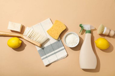 Bej arka planda doğal deterjan için havlu, fırça, sünger ve malzeme, üst görünüm