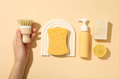 El fırçası, sünger ve deterjan bej arka planda, üst görünüm