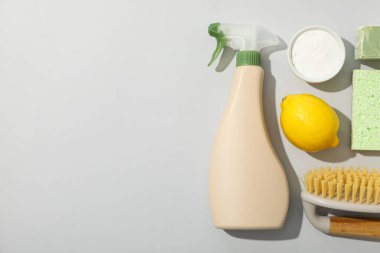 Sprey şişesi, temizlik araçları ve doğal temizlik ürünleri gri arka planda, metin için boşluk