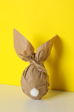 Sarı arka planda ambalajda çikolata yumurtası.