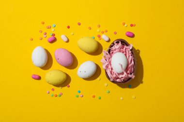 Sarı arka planda çok renkli çikolata yumurtaları.