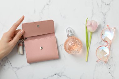 Cüzdan kadının elinde, parfüm, bardaklar ve çiçek mermer arka planda, üst manzara