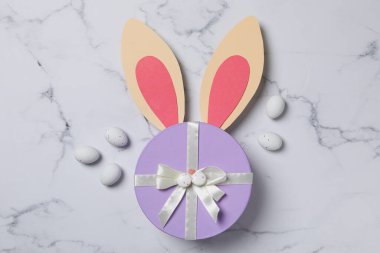 Açık arkaplanda tavşan kulakları olan mavi hediye kutusu