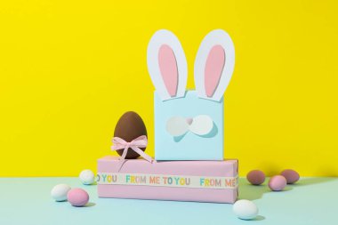 Sarı arka planda tavşan kulakları olan mavi hediye kutusu.