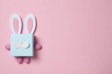 Pembe arka planda tavşan kulaklı mavi hediye kutusu