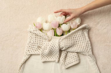 Bej şort, süveter, çiçekler ve bej arka planda el, üst manzara