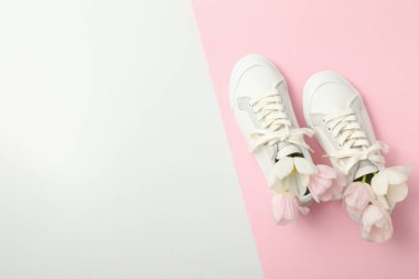 Beyaz ve pembe arka planda beyaz spor ayakkabılı çiçekler, metin için boşluk