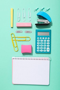 Masanın üzerinde defter ve kırtasiye malzemesi, üst görünüm.
