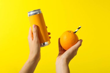 Sarı arka planda saman ve teneke kutuyla portakal