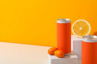 Turuncu arka planda beyaz bloklar üzerinde teneke kutular ve narenciye meyveleri, metin için boşluk