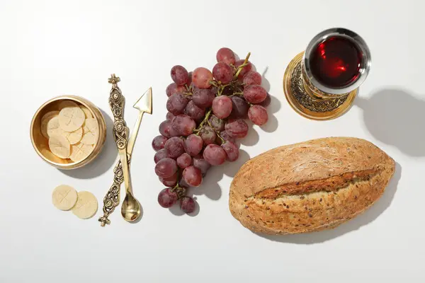 Bread, grapes, cutlery and cup of wine on white background, top view