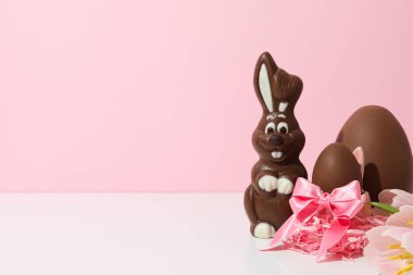 Pembe arka planda hediyeleri olan çikolatalı tavşan.