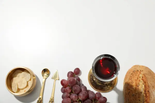 Bread, grapes, cutlery and cup of wine on white background, space for text