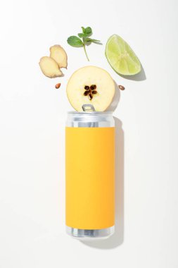 Sarı teneke kutu ve limon, beyaz arka planda elma ve zencefil parçaları, üst manzara