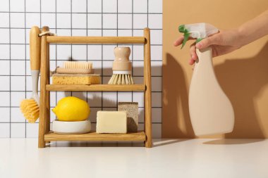 Rafta fırçalar, limon, sünger ve arka planda bir şişe deterjan.