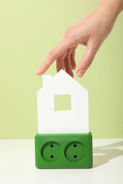 Beyaz dekoratif evi olan yeşil elektrik prizi