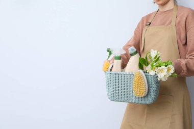 Kadının elinde deterjan dolu bir sepet.