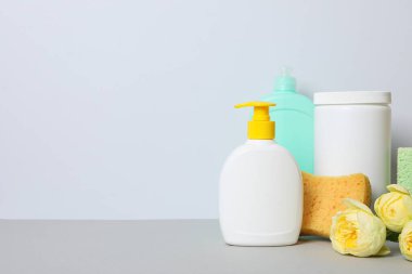 Açık arkaplanda çiçekli ve havlulu deterjanlar.