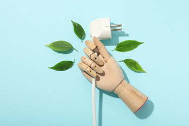 Mavi arka planda mankenin elindeki elektrik kablosu