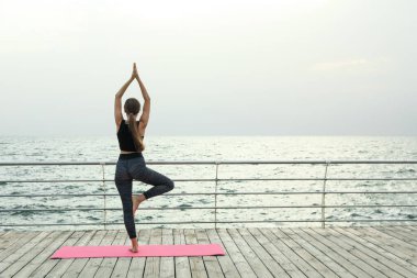 Yoga minderindeki genç kadın ahşap zeminde açık havada, mesaj için yer var.