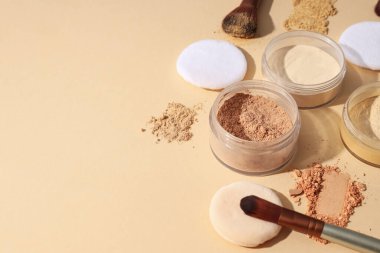 Yüz pudrası şişeleri, farklı gölgeler, pastel arka planda..