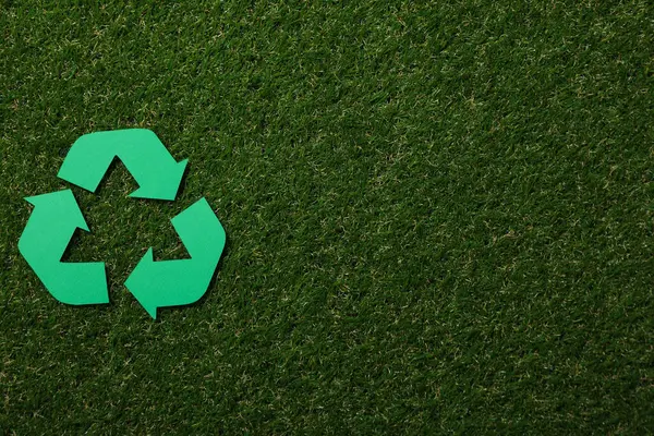 Material recycling sign on green grass background