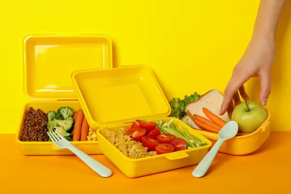 Yellow lunch box with food on a yellow background