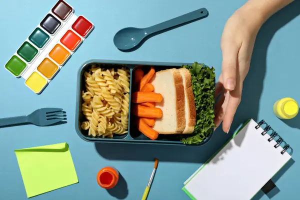 A blue lunchbox with food and drawing supplies