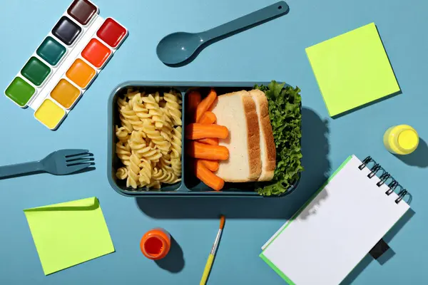 A blue lunchbox with food and drawing supplies
